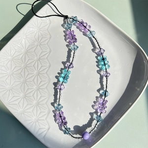 Detail of handmade beaded phone strap with purple and blue gummy bear charms on a plate