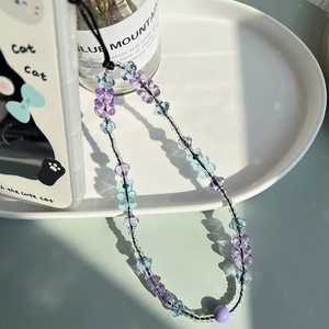 Detail of cute gummy bear phone strap with purple and blue resin beads on a ceramic tray