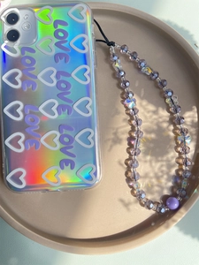 Close-up of holographic heart phone case with purple beaded charm strap and large round bead