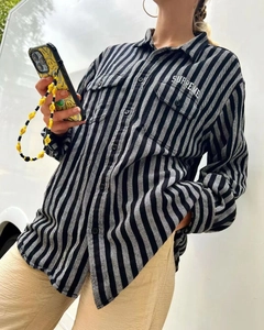 Detail of black and white vertical striped shirt with double pockets and chest logo