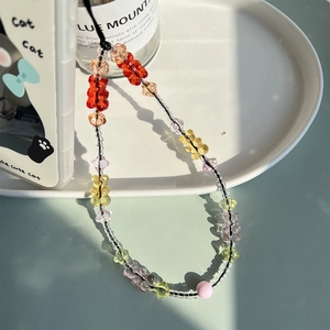 Detailed close-up of a colorful gummy bear beaded phone charm in a white ceramic tray
