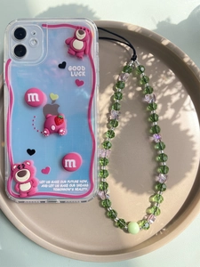 Detailed view of clear phone case with strawberry bear decor and beaded wrist strap