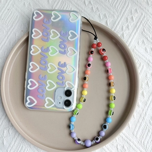 Detailed view of iridescent phone case with white hearts and colorful beaded cross-body strap