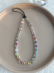Macro shot of a colorful rainbow beaded phone charm with square crystal beads on a tray