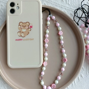 Detail of pink resin smiley face beads and floral crystals on a cream bear phone case