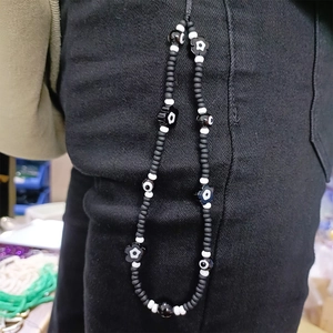 Handmade beaded flower phone charm with black and white evil eye beads on black denim