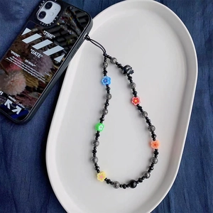 Detail of colorful flower charms and dark textured beads on an elegant phone strap