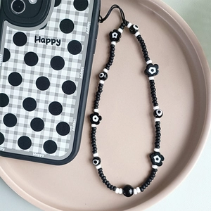 Chic black and white beaded phone charm with floral accents and a matching checkered case