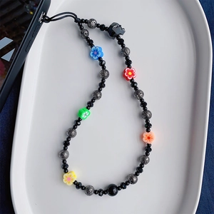 Detail of beaded phone strap featuring skull charm and colorful floral beads on dark cord