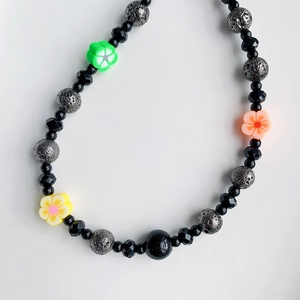 Detailed macro view of handmade beaded phone strap with black beads and clay flowers
