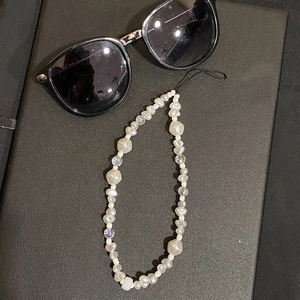 Minimalist phone charm with white faux pearls and clear faceted beads on black texture