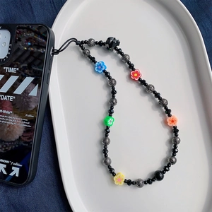 Macro view of handmade beaded phone strap with colorful resin flowers and black beads