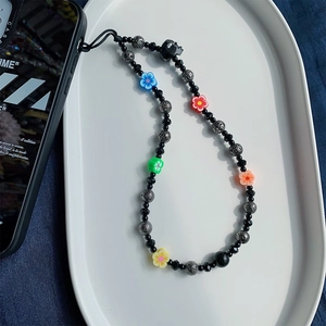 Colorful beaded phone strap with crystal skull beads and flower charms in a white tray