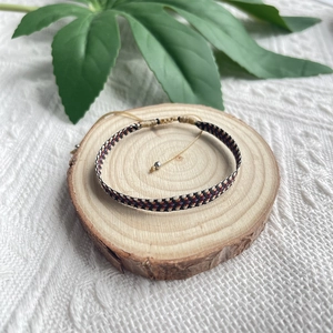 Vue détaillée d'un bracelet d'amitié tissé ethnique avec motifs sur bois naturel