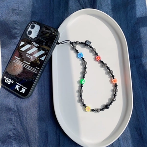Detailed macro view of beaded phone strap with colorful flowers on a black case