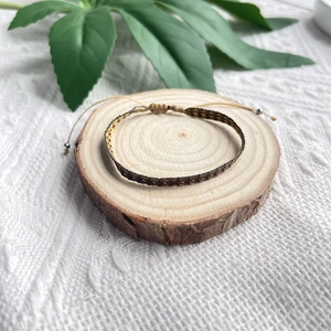 Détail d'un bracelet tressé bohème avec motifs ethniques sur un plateau en bois et dentelle