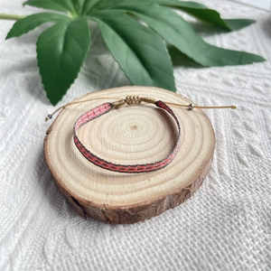 Détail d'un bracelet tribal tissé à la main sur bois rustique et base de feuille verte