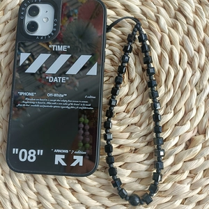 Detail of mirror-finish black phone case with geometric beaded strap on woven mat