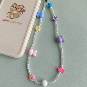 Cute bunny phone charm with colorful beads and flower pendants on green background