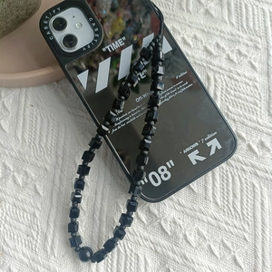Detail of minimalist black square beaded phone strap on textured white fabric background