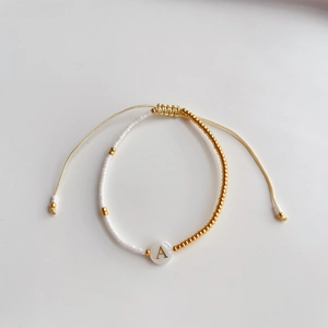 Detail van handgemaakte kralenarmband met letter A en verstelbaar koord