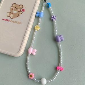Detail of beaded phone strap with acrylic rabbit and colorful flower charms on phone case