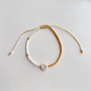Macrodetail van Franse stijl kralenarmband met witte rijstkralen en gouden accenten