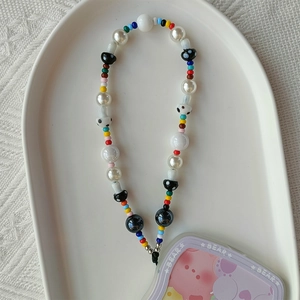 Detail of beaded phone wrist strap with white and black polka dot mushroom charms