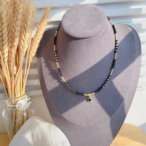 Detail van kralenketting met zwarte sterhanger op een grijze display met tarwe