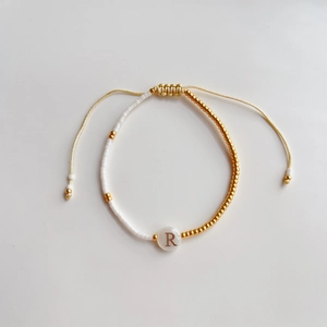 Macro-opname van een handgemaakte kralenarmband met gouden kralen en de letter R