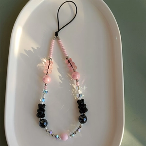 Macro view of beaded phone strap with pink gummy bears and black polished round beads