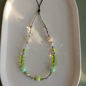 Macro view of crystal beaded phone strap featuring green gummy bears and iridescent beads