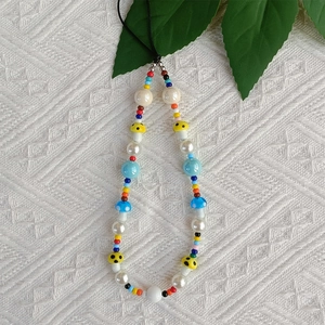 Detailed view of colorful beaded phone strap with cute mushroom charms and pearls