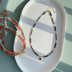 Boheemse kralenketting met zwarte sterhanger en kleurrijke kristalaccenten op een blad