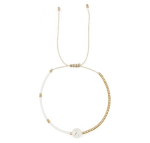 Detail van een handgemaakte kralenarmband met witte kralen en een gouden letter Z-bedel