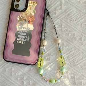 Detail of purple wavy iPhone case with gummy bear beaded charm on white fabric