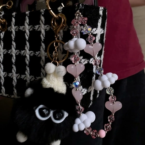 Plush monster keychain with pink heart beads and cloud charms on a checkered handbag