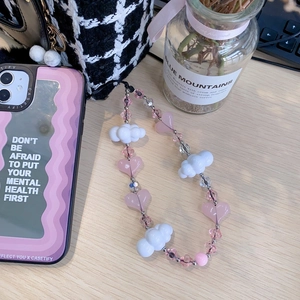 Pink heart and white cloud beaded phone strap on light wood desk with accessories