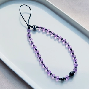 Purple amethyst beaded phone charm with evil eye accents on a white display tray
