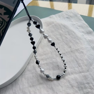 Black heart crystal phone strap with irregular pearls and minimalist beads on tray