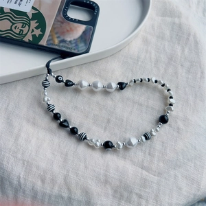 Handmade beaded phone strap with black hearts, white pearls, and striped beads for wrist