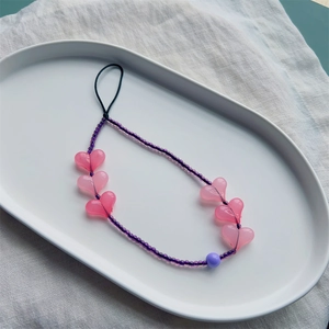 Bijou de téléphone perlé avec cœurs en acrylique rose et perles mauves sur plateau