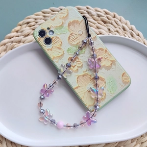 Handmade beaded phone strap with crystal butterflies on a floral case in a white tray
