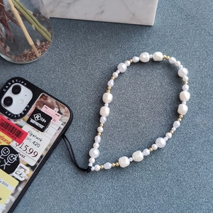 Handmade baroque pearl phone strap with gold beads on a minimalist grey background