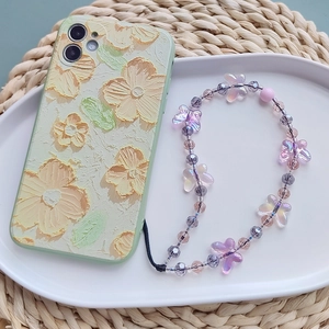 Green embossed floral phone case with crystal butterfly beaded lanyard on a tray