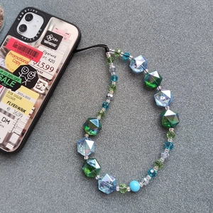 Close-up of colorful iridescent faceted beads on a green and blue crystal phone strap