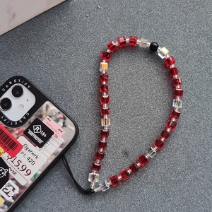 Handmade phone strap with dark red cube crystals and iridescent beads on a grey surface