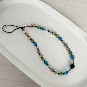 Colorful cube crystal phone charm strap with vibrant faceted beads on a white tray