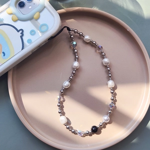 Elegant baroque pearl and silver bead phone strap wristlet displayed on a ceramic plate