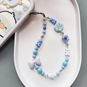 Cute beaded phone strap with blue resin bows and bears on a ceramic tray display